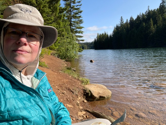 Picture of me on a shoreline in full sun, wearing coat & hat