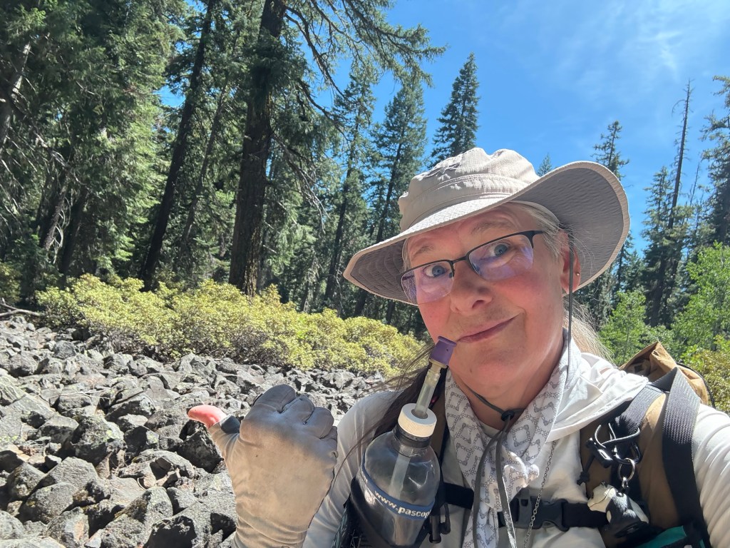 Selfie of me, pointing at the lava field with me thumb
